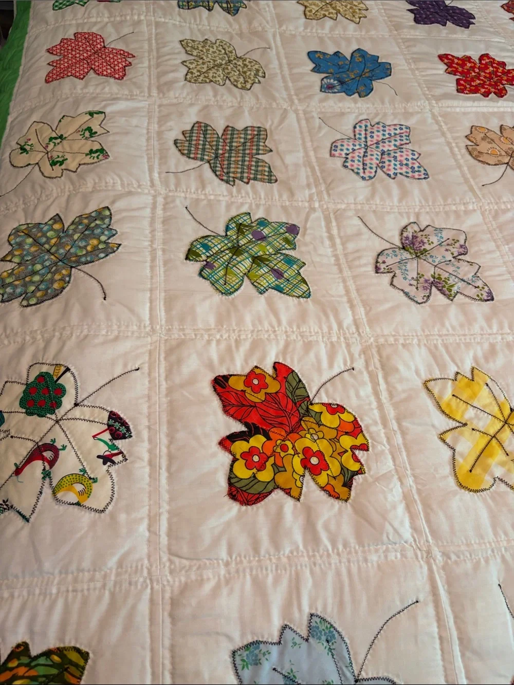 Vintage quilt handcrafted with color leaf blocks on white with green trim